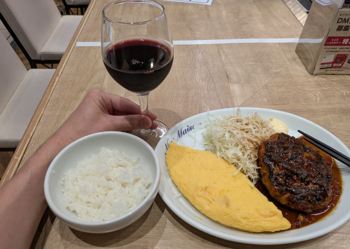 ハンバーグとオムレツをおつまみに赤ワインを飲む様子